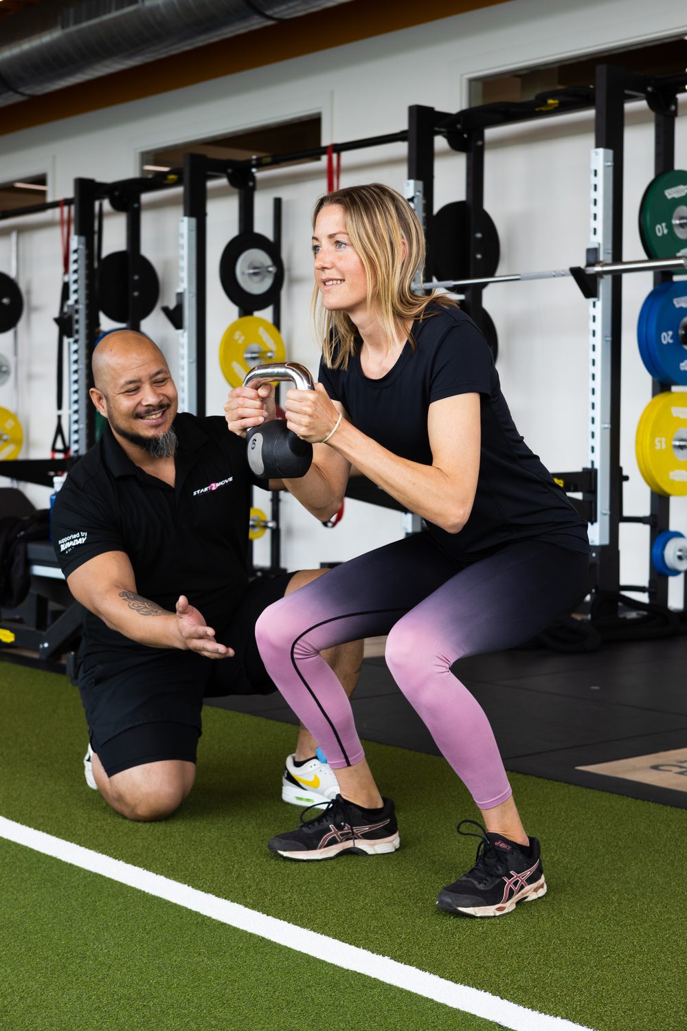 Marco coacht een klant tijdens een kettlebell squat